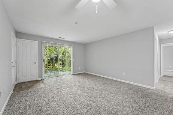 A spacious room with a carpeted floor and a ceiling fan.